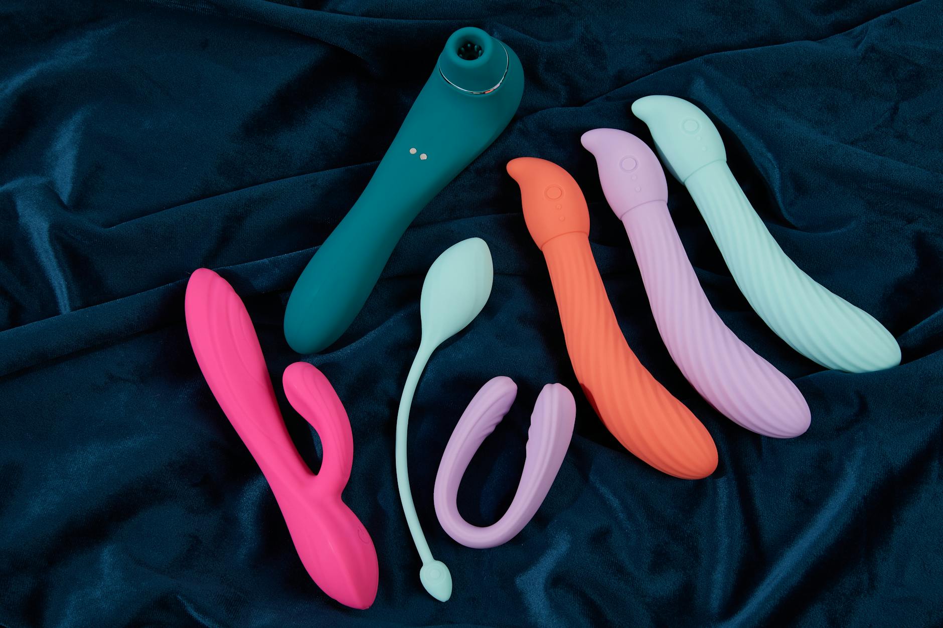 Vibrant collection of silicone sex toys arranged on bright yellow surface