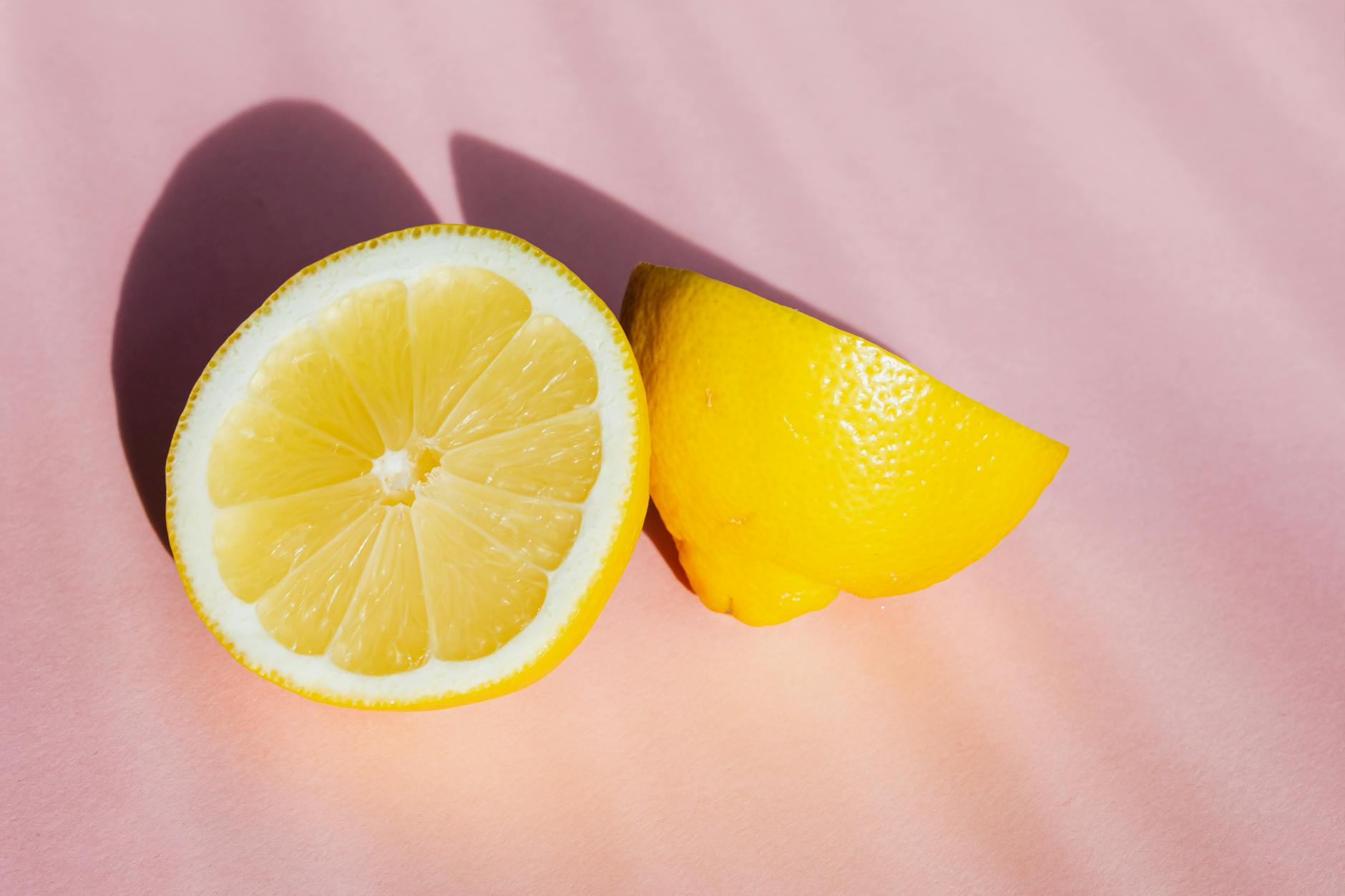 Fresh lemon halves on a pink background in natural sunlight, symbolizing hormonal freshness and sensitivity
