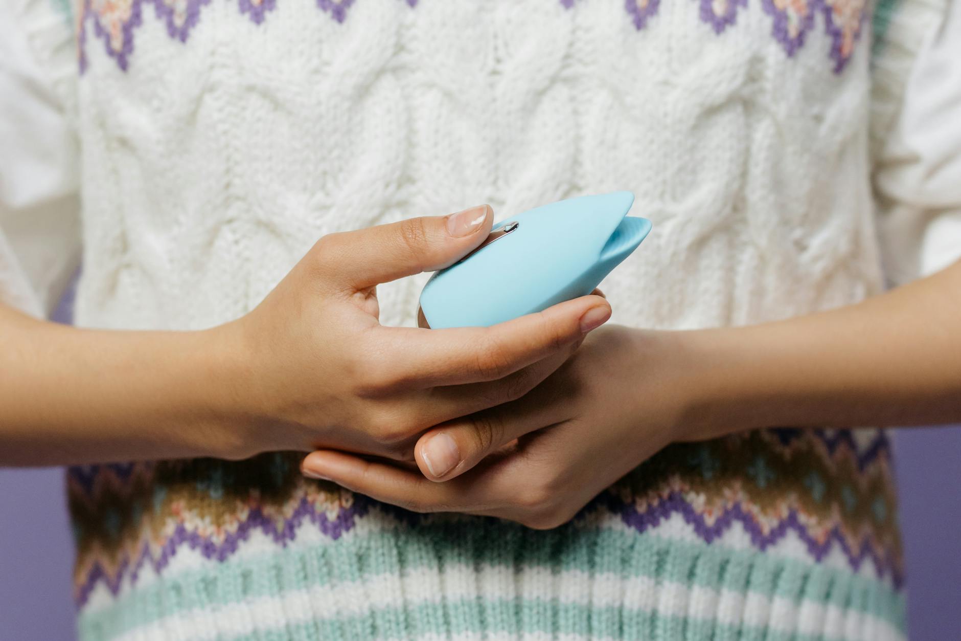 Close-up of hands holding a lemon vibrator against a knitted sweater, showing intimate comfort with lemon sexual toys.