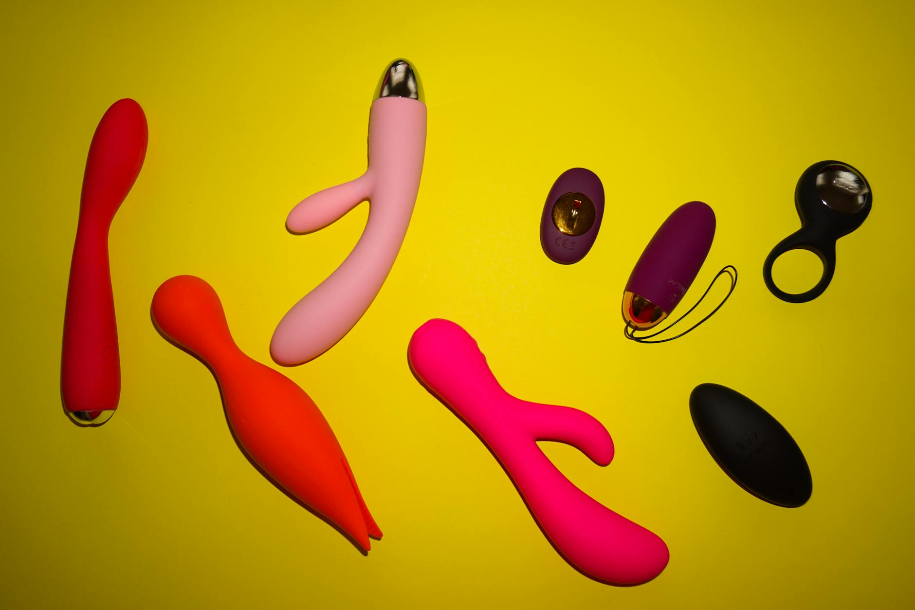 Vibrant arrangement of colorful lemon vibrators and sex toys on a bright yellow surface